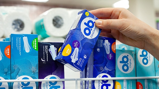 Image of a person picking up a box of tampons off the shelf