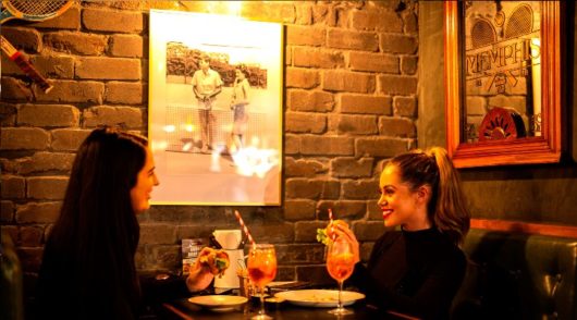 two girls enjoying cocktails in a bar
