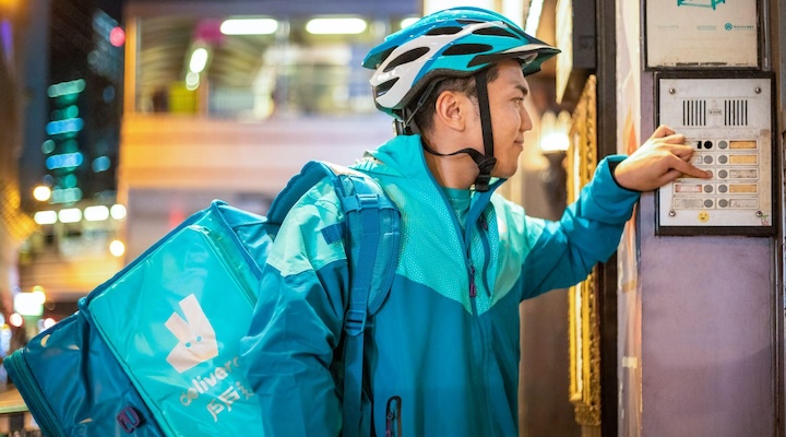 An image of a Deliveroo rider ringing a doorbell to deliver an order to a customer