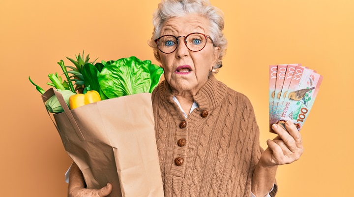 senior woman holding groceries and NZ dollars