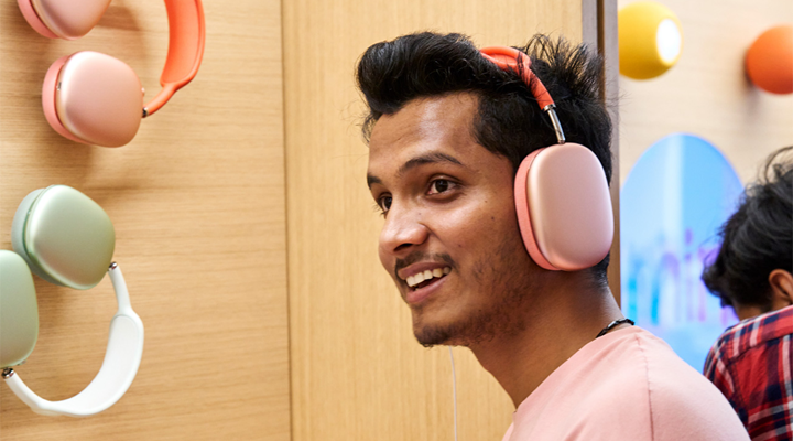 A man trying on a pair of pink headphones in an Apple store