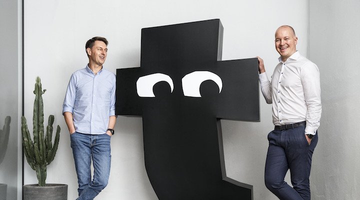 Flying Tiger executives stand next to a large sculpture of the company's logo