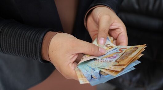 A woman holds New Zealand banknotes