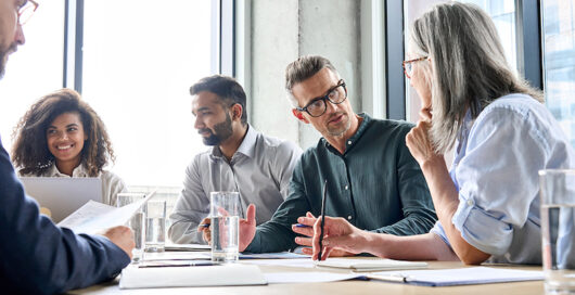 Diverse business people partners group negotiating at boardroom meeting. Multiethnic executive team discussing financial partnership agreement project strategy brainstorming sitting at table in office.