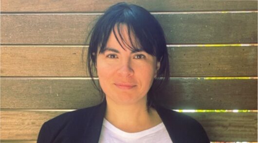 IHG head of digital Anna Kismet standing against a wooden fence and smiling