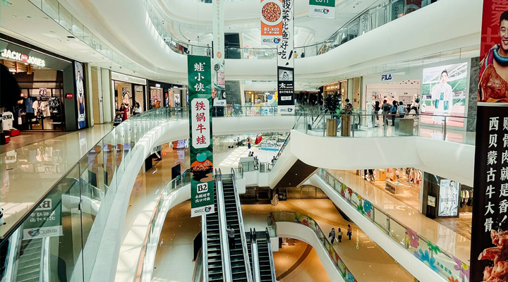 An interior shot of a shopping mall in China, showing escalators and storefronts.