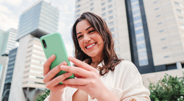 A woman smiling and looking at a smartphone.