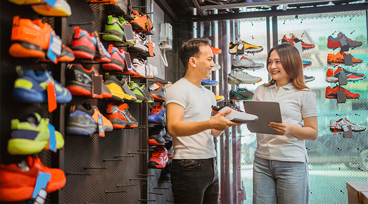 Adidas store staff member shows shoes to customer.