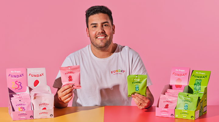 Image of funday founder daniel kitay sitting at a table wearing a branded t-shirt and holding his product