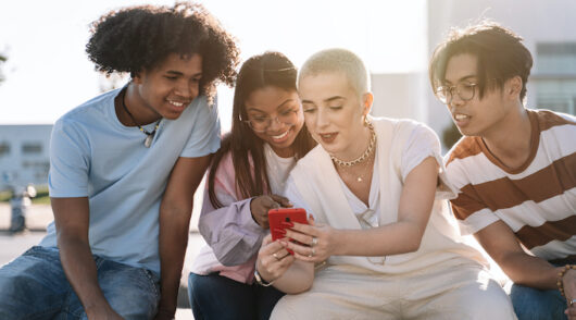 group of gen z friends looking at a smart phone