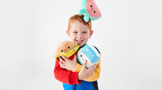 A campaign image showing a red-haired boy holding multiple stuffed toys