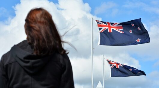 A woman stands under New Zealand flag