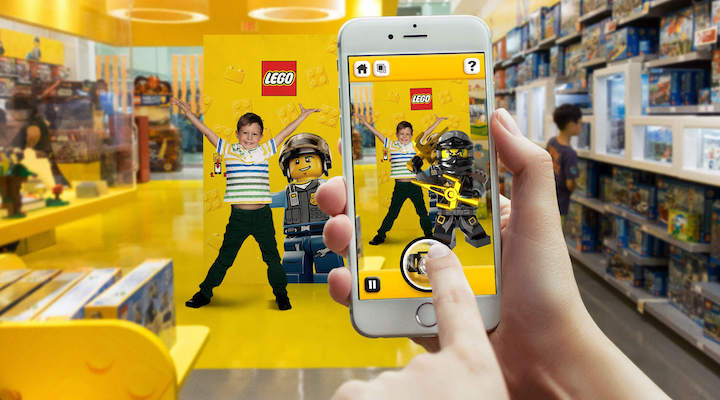 An interior shot of a Lego store with a young kid holding a phone and engaging in an interactive activity.