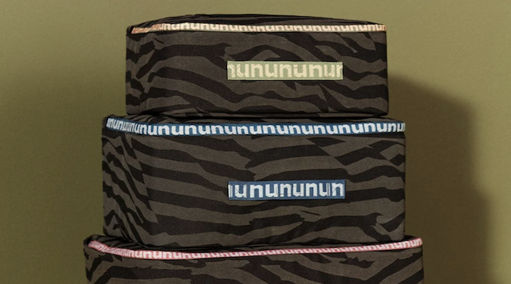 A stack of Nuuly delivery boxes against an olive-green background.