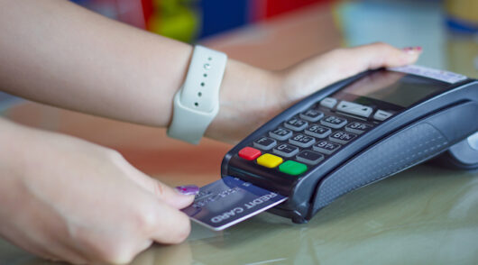 Image of person swiping card in payment machine.