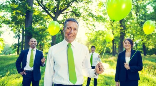 Group of Business People Holding Green Balloons in Forest