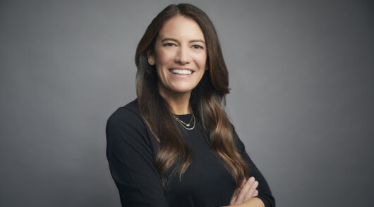 A headshot photo of Coach’s North America Leigh Manheim Levine in front of a dark gray background.