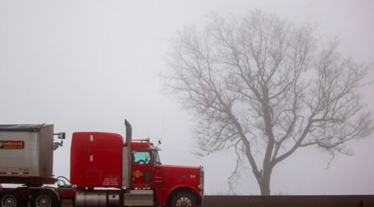 Red truck on misty highway.