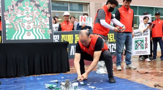 An activist smashes Starbucks tumblers and mugs during a protest against Starbucks' "Tank Day" campaign