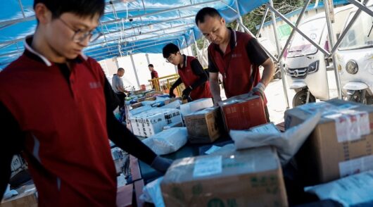 Delivery workers sort packages on a conveyor belt amid the "618" shopping festival, at a logistics station in Beijing