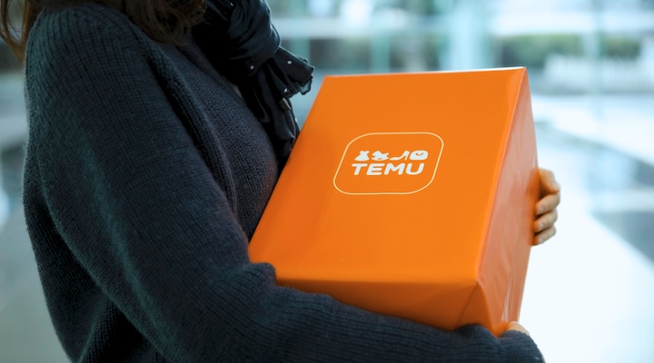 a person holding an orange Temu box