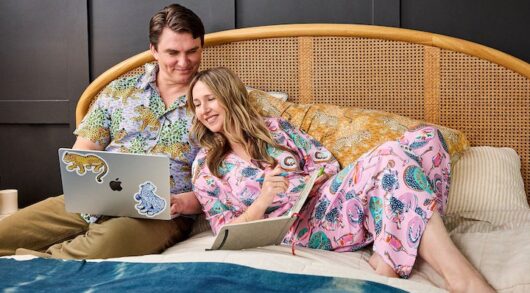 Amy Voloshin and her husband lying on a bed wearing Printfresh pajamas.